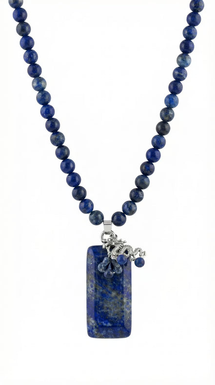 Colier pe fundal alb din mărgele sferice albastre lapis lazuli și pandantiv dreptunghiular cu element metalic dragon.