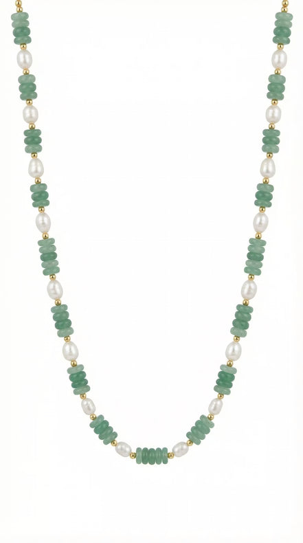Colier desfășurat pe fundal alb compus din șirag subțire de pietre verzi și element central din perlă albă alungită cu închidere argintie.