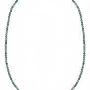 Colier desfășurat pe fundal alb compus din șirag subțire de pietre verzi și element central din perlă albă alungită cu închidere argintie.