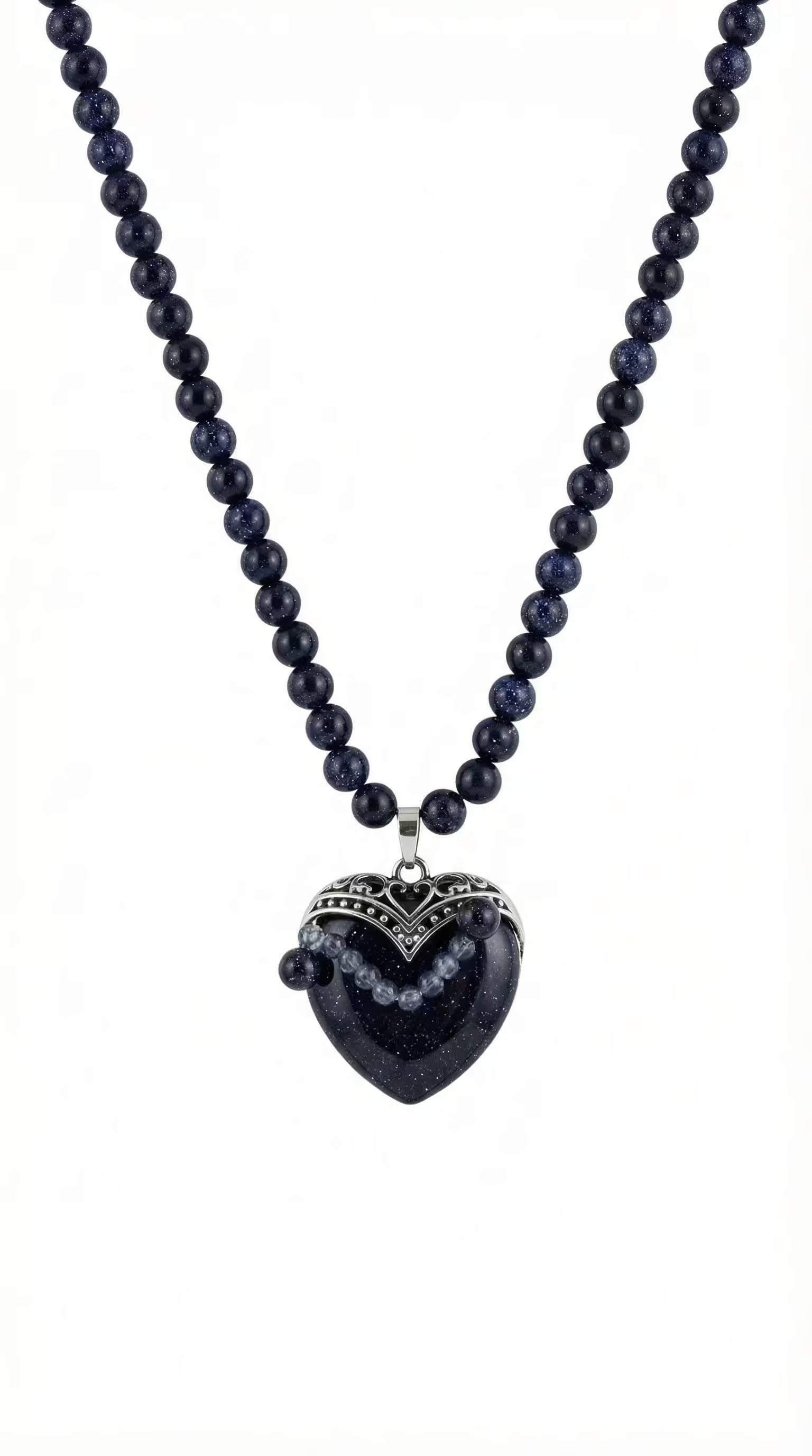 Colier pe fundal alb din mărgele albastre sclipitoare și pandantiv mare în formă de inimă cu montură argintie filigranată.