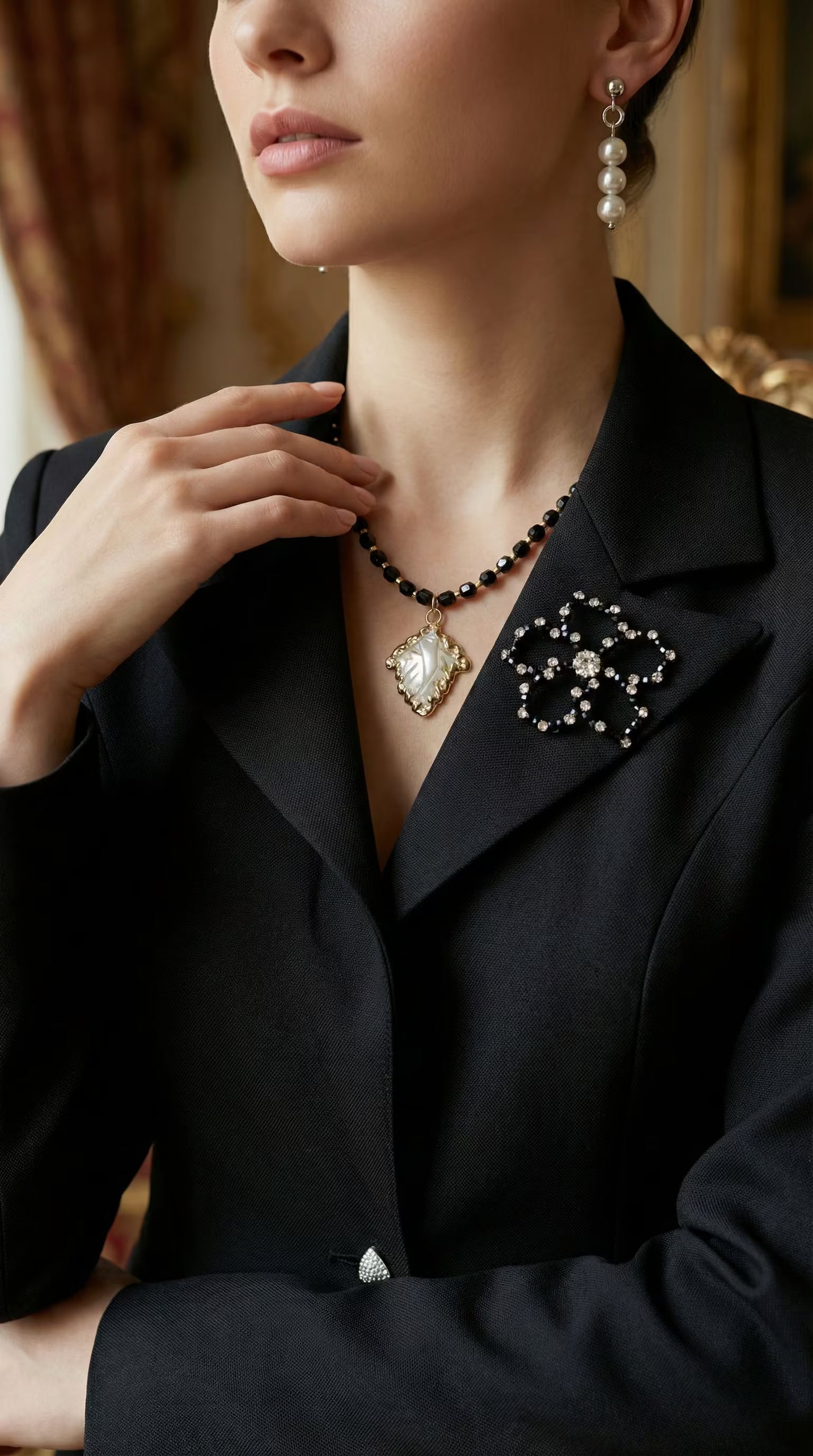 Prim-plan cu reverul satinat al unui sacou negru decorat cu o broșă în formă de floare din cristale negre și transparente.