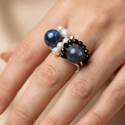 Prim-plan cu inelul purtat pe deget evidențiind textura perlelor albe în contrast cu sferel albastre de lapis lazuli.