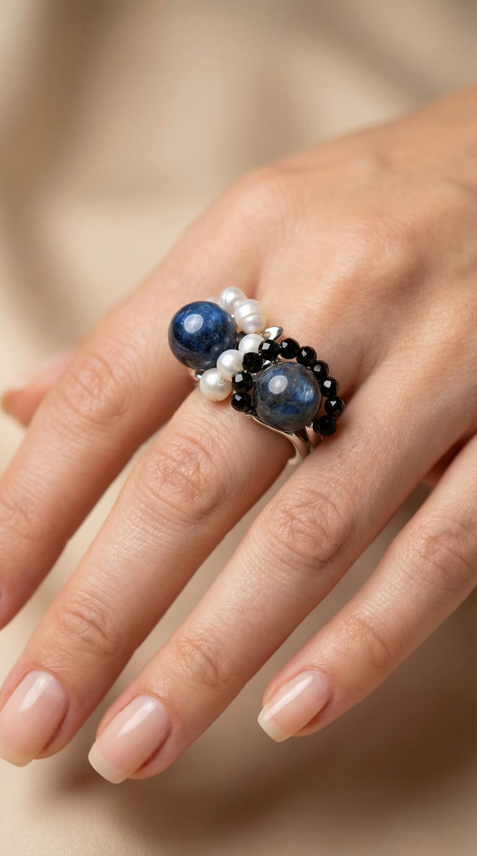 Prim-plan cu inelul purtat pe deget evidențiind textura perlelor albe în contrast cu sferel albastre de lapis lazuli.
