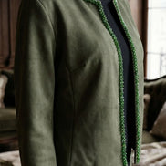 Prim-plan cu jacheta verde din suedine purtată peste un top negru evidențiind șiragul de cristale fațetate de pe marginea deschiderii.