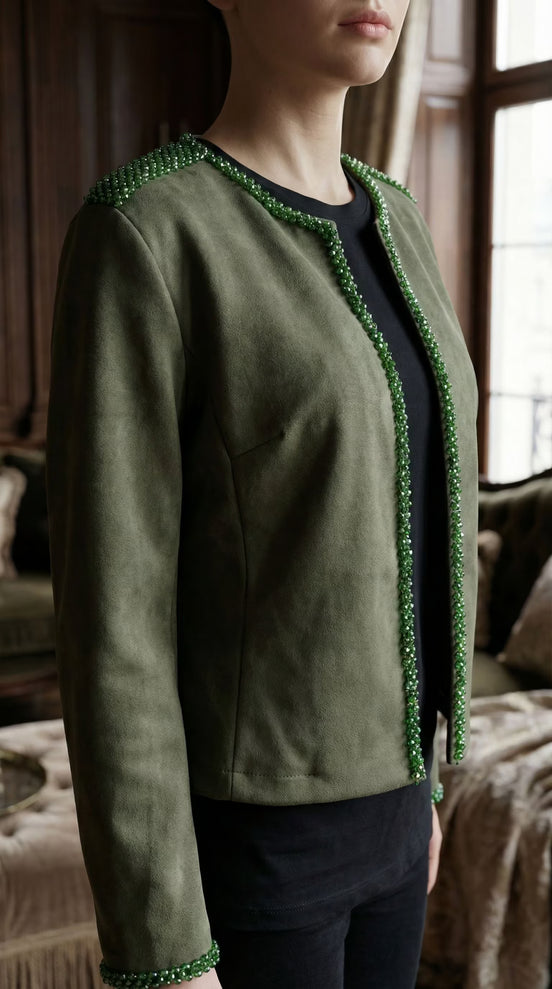 Prim-plan cu jacheta verde din suedine purtată peste un top negru evidențiind șiragul de cristale fațetate de pe marginea deschiderii.