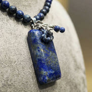 Prim-plan macro cu pandantivul dreptunghiular albastru cu incluziuni aurii și montură sub formă de dragon argintiu.