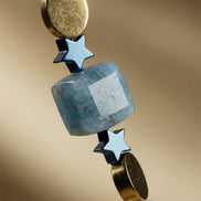 Prim-plan macro evidențiind secvența de mărgele cubice bleu stele metalice albastre discuri aurii și perle naturale inelate.