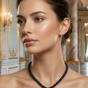 Femeie purtând un colier elegant cu inimă albastră la o ținută de seară bej cu umerii goi într-un decor clasic.