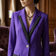 Femeie purtând un sacou violet cu accente negre și cristale într-un decor elegant asortat cu cercei și colier mov.